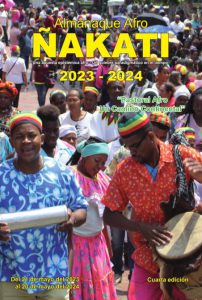 Portada del Almanaque Afro Ñakati con el título "Pastoral Afro: un camino continental". 2 jóvenes afro, uno con una tambora y otro con un güiro, lideran un procesión afro con vestidos típicos coloridos